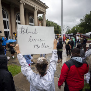 A group of protesters gather outside the Glynn County Courthouse while a preliminary hearing is being held inside for for Travis McMichael, Gregory McMichael and William Bryan, Thursday, June 4, 2020, in Brunswick, Ga. The three are accused of shooting of Ahmaud Arbery while he ran through their neighborhood in February. (AP Photo/Stephen B. Morton)