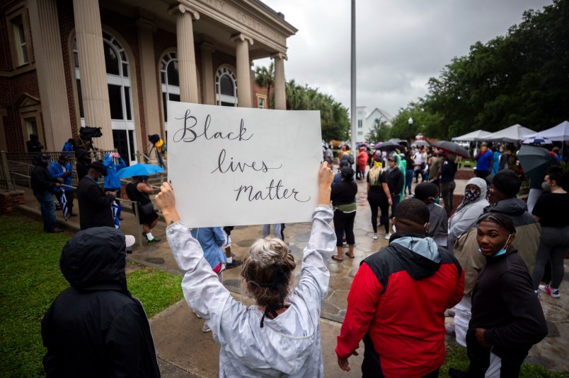 A group of protesters gather outside the Glynn County Courthouse while a preliminary hearing is being held inside for for Travis McMichael, Gregory McMichael and William Bryan, Thursday, June 4, 2020, in Brunswick, Ga. The three are accused of shooting of Ahmaud Arbery while he ran through their neighborhood in February. (AP Photo/Stephen B. Morton)