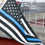 PORTLAND, ME - APRIL 8: Tim Seavey of Westbrook holds a Thin Blue Line flag next to grandson Ladainian Seavey on Tuesday at Harbor View Memorial Park as a motorcade accompanies fallen Maine State Police detective Ben Campbell’s casket across Casco Bay Bridge toward his funeral at Cross Insurance Arena. Seavey, who flies the flag year round at home, said he brough his grandson to the processional to teach him about respect for law enforcement. (Staff photo by Ben McCanna/Staff Photographer)