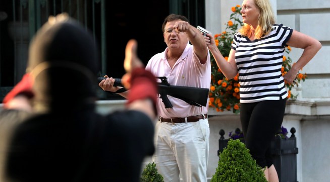 Armed homeowners standing in front of their house along Portland Place confront protesters as they march to Mayor Lyda Krewson's house on Sunday, June 28, 2020, in the Central West End in St. Louis. (Laurie Skrivan/St. Louis Post-Dispatch/TNS)