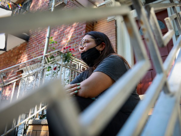 Natalia Afonso, 27, an international student from Brazil at Brooklyn College, sit on a stoop outside her home during an interview, Thursday July 9, 2020, in New York.  Afonso, who is studying teaching education and finished her first semester this spring, said she has lived in the U.S. for 7 years and “I don’t see myself moving back to Brazil at this point.  (AP Photo/Bebeto Matthews)