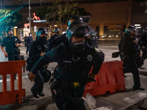 Police chase after protesters who refused to disperse at a protest on Saturday, July 25, 2020, in Oakland, Calif. The protest was organized in support of the city of Portland and against the presence of federal agents in US cities.(AP Photo/Christian Monterrosa)