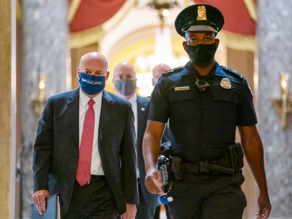 Postmaster General Louis DeJoy, left, is escorted to House Speaker Nancy Pelosi’s office on Capitol Hill in Washington, Wednesday, Aug. 5, 2020. Some clarity is beginning to emerge from the bipartisan Washington talks on a huge COVID-19 response bill. An exchange of offers and meeting devoted to the Postal Service on Wednesday indicates the White House is moving slightly in House Speaker Nancy Pelosi’s direction on issues like aid to states and local governments and unemployment insurance benefits. But the negotiations have a long ways to go. (AP Photo/Carolyn Kaster)