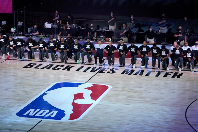Members of the Milwaukee Bucks and the Boston Celtics kneel around a Black Lives Matter logo before the start of an NBA basketball game Friday, July 31, 2020, in Lake Buena Vista, Fla. (AP Photo/Ashley Landis, Pool)