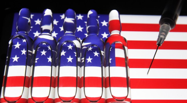 UKRAINE - 2020/11/13: In this photo illustration a syringe and  ampules with fake COVID-19 vaccine seen with the U.S flag in the background. (Photo Illustration by Pavlo Conchar/SOPA Images/LightRocket via Getty Images)