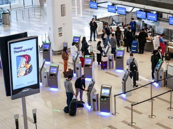 Travelers wait to check-in for their flights at LaGuardia Airport, Wednesday, Nov. 25, 2020, in the Queens borough of New York. Millions of Americans are taking to the skies and hitting the road ahead of Thanksgiving at the risk of pouring gasoline on the coronavirus fire. They are disregarding increasingly dire warnings that they stay home and limit their holiday gatherings to members of their own household. (AP Photo/John Minchillo)