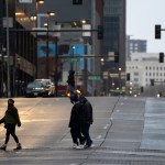 Pedestrians wear masks while crossing an empty road at the intersection of Market Street and 15th Avenue during the evening rush hour Monday, Dec. 28, 2020, in downtown Denver. (AP Photo/David Zalubowski)