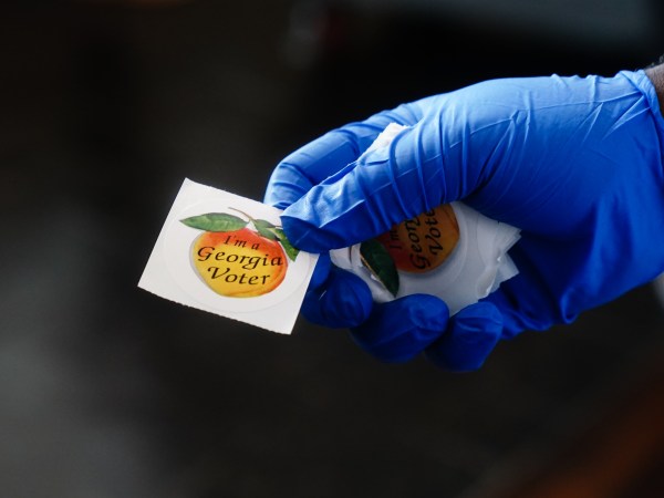 ATLANTA, GA - JUNE 09: A polling place worker holds an "I'm a Georgia Voter" sticker to hand to a voter on June 9, 2020 in Atlanta, Georgia. (Photo by Elijah Nouvelage/Getty Images)