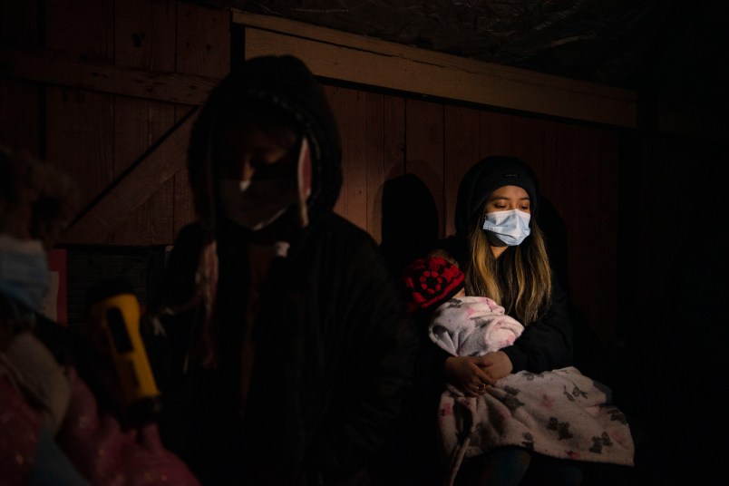 HOUSTON, TX - FEBRUARY 18: Surrounded by tarp and bedsheets, Evelyn Hernandez, 15, and her sister, Daeslyn Hernandez, 1, keep warm by the glow of a camping stove on their family’s front porch following an unprecedented winter storm in Houston, Texas on February 18, 2021. The Hernandez family lost power on Monday morning and are preparing for another deep freeze.  (Photo by Callaghan O’Hare for The Washington Post)