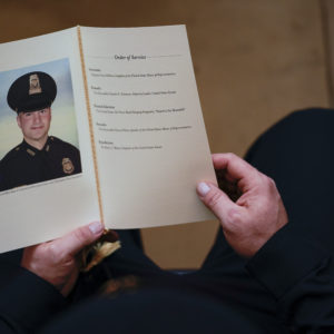 WASHINGTON, DC - FEBRUARY 3: A U.S. Capitol Police Officer holds a program for the ceremony memorializing U.S. Capitol Police Officer Brian D. Sicknick, 42, as he lies in honor in the Rotunda of the Capitol on Wednesday, February 3, 2021. Officer Sicknick was responding to the riot at the U.S. Capitol on Wednesday, January 6, 2021, when he was fatally injured while physically engaging with the mob. Members of Congress will pay tribute to the officer on Wednesday morning before his burial at Arlington National Cemetery. (Photo by Demetrius Freeman/The Washington Post/POOL)