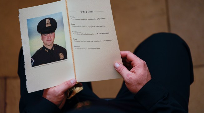 WASHINGTON, DC - FEBRUARY 3: A U.S. Capitol Police Officer holds a program for the ceremony memorializing U.S. Capitol Police Officer Brian D. Sicknick, 42, as he lies in honor in the Rotunda of the Capitol on Wednesday, February 3, 2021. Officer Sicknick was responding to the riot at the U.S. Capitol on Wednesday, January 6, 2021, when he was fatally injured while physically engaging with the mob. Members of Congress will pay tribute to the officer on Wednesday morning before his burial at Arlington National Cemetery. (Photo by Demetrius Freeman/The Washington Post/POOL)