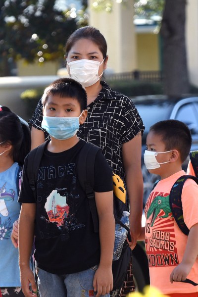 ORLANDO, FLORIDA, UNITED STATES - 2021/08/10: Students wearing face masks arrive on the first day of classes for the 2021-22 school year at Baldwin Park Elementary School. Due to the current surge in COVID-19 cases in Florida, Orange County public schools have implemented a face mask mandate for students for 30 days unless a parent chooses to opt out of the requirement. (Photo by Paul Hennessy/SOPA Images/LightRocket via Getty Images)