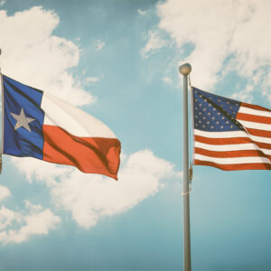 The state flag of Texas and American flag waving in the wind on flagpoles