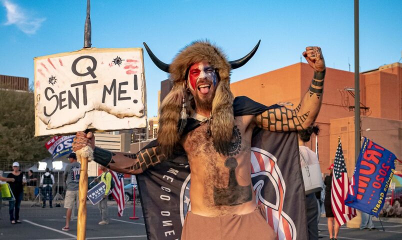 Jake A, 33, aka Yellowstone Wolf, from Phoenix, holds a QAnon sign, as he presents himself as a shamanist and consultant for the Trump supporters gathered in front of the Maricopa County Election Department where ballots are counted after the US presidential election in Phoenix, Arizona, on November 5, 2020. - President Donald Trump erupted on November 5 in a tirade of unsubstantiated claims that he has been cheated out of winning the US election as vote counting across battleground states showed Democrat Joe Biden steadily closing in on victory. (Photo by OLIVIER  TOURON / AFP) (Photo by OLIVIER  TOURON/AFP via Getty Images)