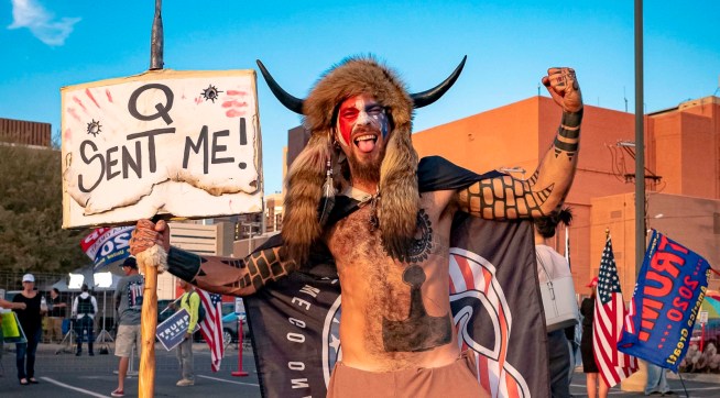 Jake A, 33, aka Yellowstone Wolf, from Phoenix, holds a QAnon sign, as he presents himself as a shamanist and consultant for the Trump supporters gathered in front of the Maricopa County Election Department where ballots are counted after the US presidential election in Phoenix, Arizona, on November 5, 2020. - President Donald Trump erupted on November 5 in a tirade of unsubstantiated claims that he has been cheated out of winning the US election as vote counting across battleground states showed Democrat Joe Biden steadily closing in on victory. (Photo by OLIVIER  TOURON / AFP) (Photo by OLIVIER  TOURON/AFP via Getty Images)