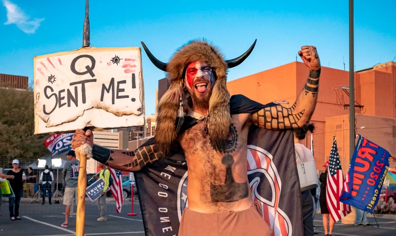 Jake A, 33, aka Yellowstone Wolf, from Phoenix, holds a QAnon sign, as he presents himself as a shamanist and consultant for the Trump supporters gathered in front of the Maricopa County Election Department where ballots are counted after the US presidential election in Phoenix, Arizona, on November 5, 2020. - President Donald Trump erupted on November 5 in a tirade of unsubstantiated claims that he has been cheated out of winning the US election as vote counting across battleground states showed Democrat Joe Biden steadily closing in on victory. (Photo by OLIVIER  TOURON / AFP) (Photo by OLIVIER  TOURON/AFP via Getty Images)