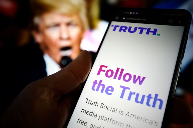The TRUTH Social website is seen on a mobile device with an image of former US president Donald Trump in the background in this photo illustration in Warsaw, Poland on 23 February, 2022. TRUTH Social is a newly developed social media platform by the Trump Media and Technology Group (TMTG) modelled after Twitter. The initiative was taken after Trump himself had been banned from Facebook and Twitter in 2021. (Photo by STR/NurPhoto)