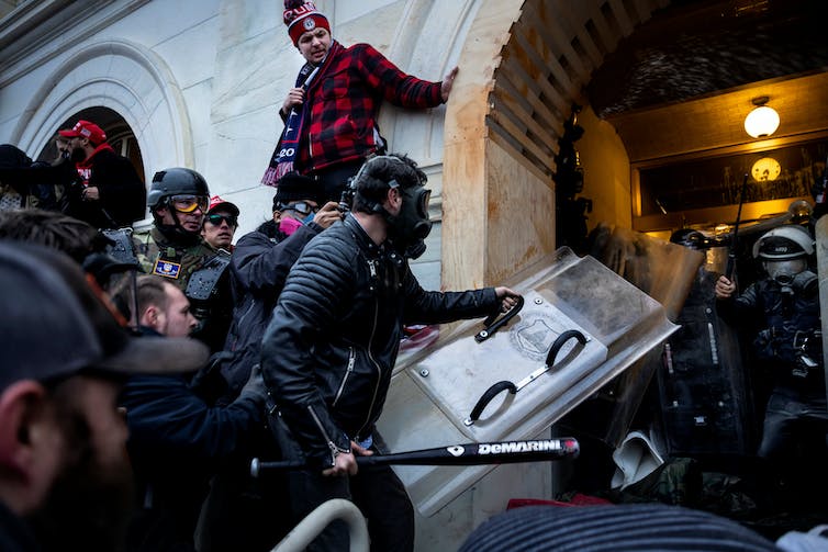 With some wielding weapons and wearing protective gear, rioters clash with police on the steps of an entrance to the U.S. Capitol.